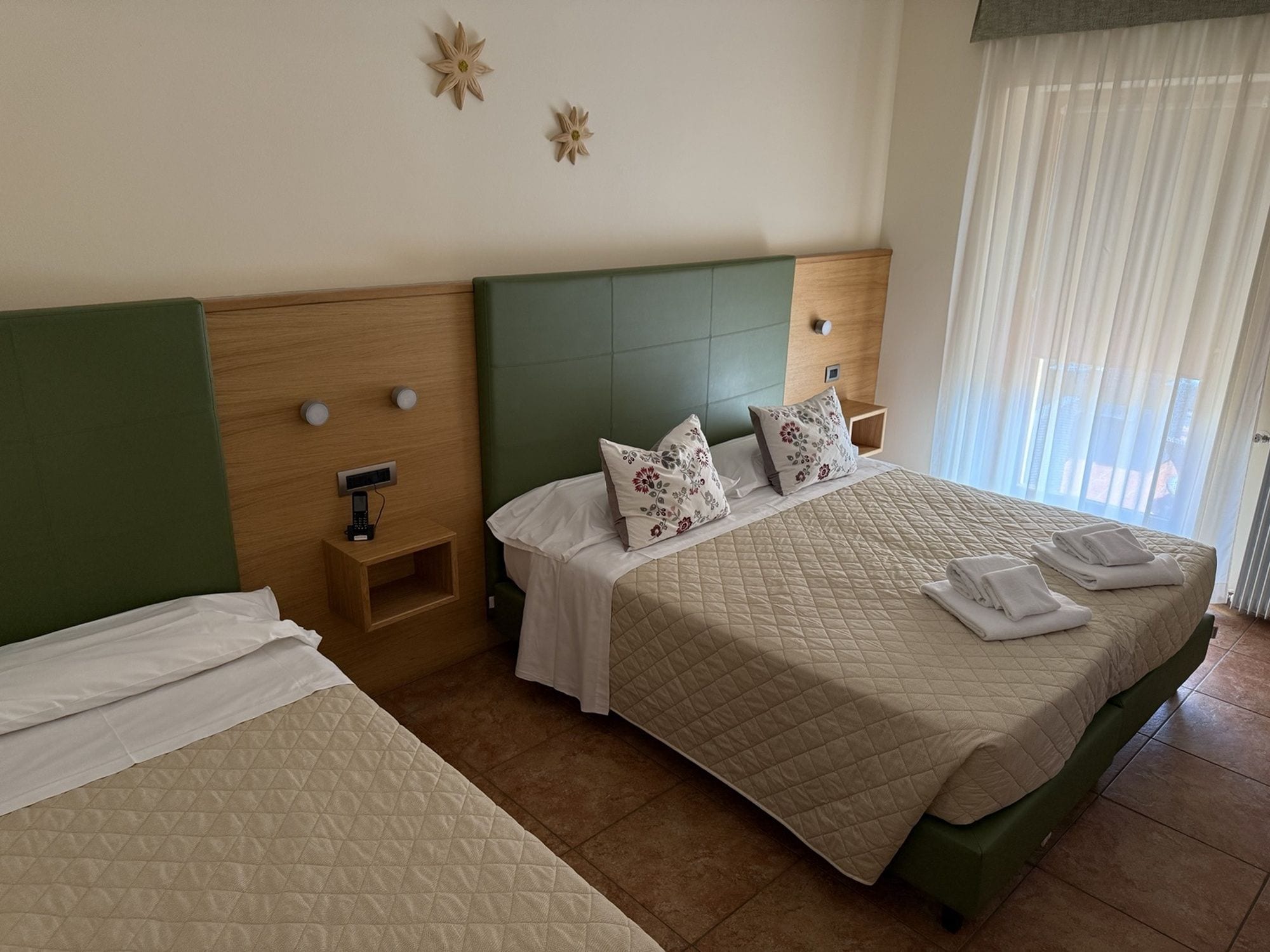 Habitación de hotel con cama, mesita de noche y panel de control en la pared.