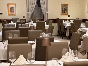 A restaurant interior with multiple tables, chairs, and dining tables. - Hotel Trieste (Tarvisio)