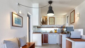 A compact kitchen with a bench, a dining area, and a hanging light fixture.