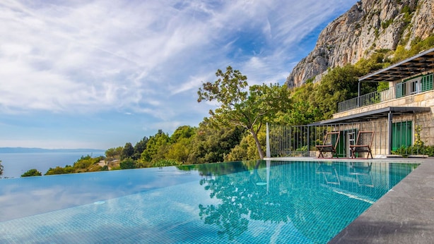 A infinity pool with a clear view of the sea and a rocky cliff.
