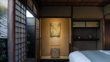 Une pièce de style japonais traditionnel, avec un sol recouvert de tatamis, un lit bas en bois, un paravent shoji et une lanterne suspendue.