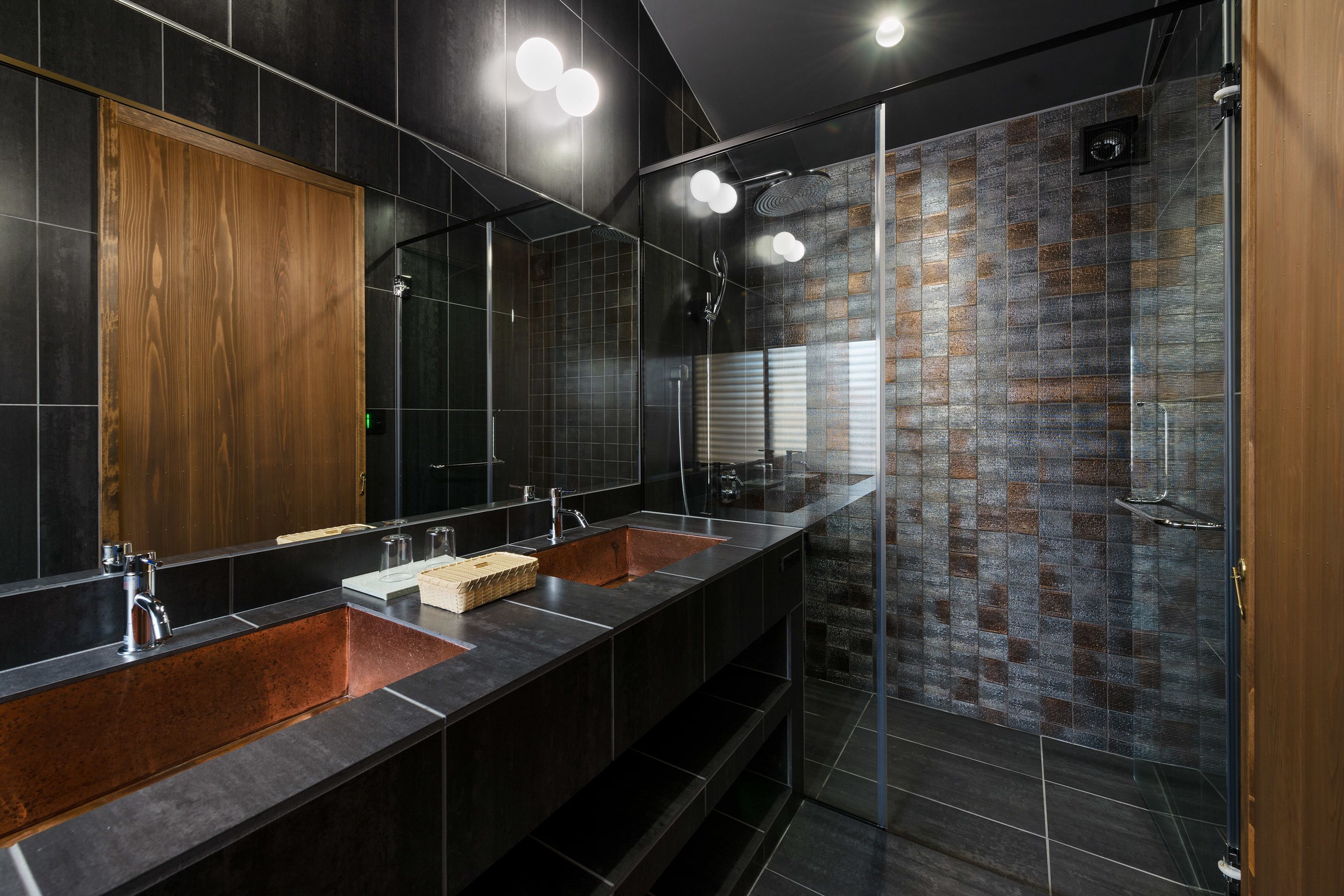 A modern bathroom with a large mirror, two sinks, and a glass-enclosed shower.