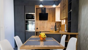 Une cuisine moderne avec des meubles en bois, un four encastré, un four à micro-ondes et une table à manger avec quatre chaises.