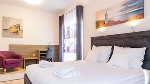 Une chambre d’hôtel avec un lit, un bureau, une chaise et un tableau au mur.