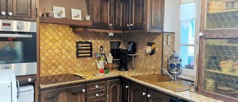 A kitchen with wooden cabinets, a stainless steel oven, a coffee maker, and a sink.