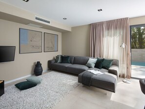 Ein modernes Wohnzimmer mit einem grauen Ecksofa, einem Flachbildfernseher und Kunstwerken an der Wand.