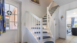 Eine Treppe mit weißen Geländern und blau beflasterten Stufen, die zu einer oberen Etage führt.