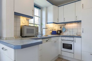 Uma cozinha com armários brancos, micro-ondas, lava-louças e forno.