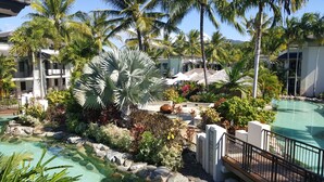 A resort with a swimming pool, palm trees, and a well-maintained garden.