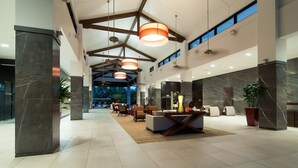 A spacious lobby with marble columns, a reception desk, and a seating area with sofas and a coffee table.