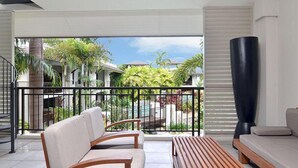 A modern living room with a balcony, featuring a sofa, chairs, and a wooden coffee table.
