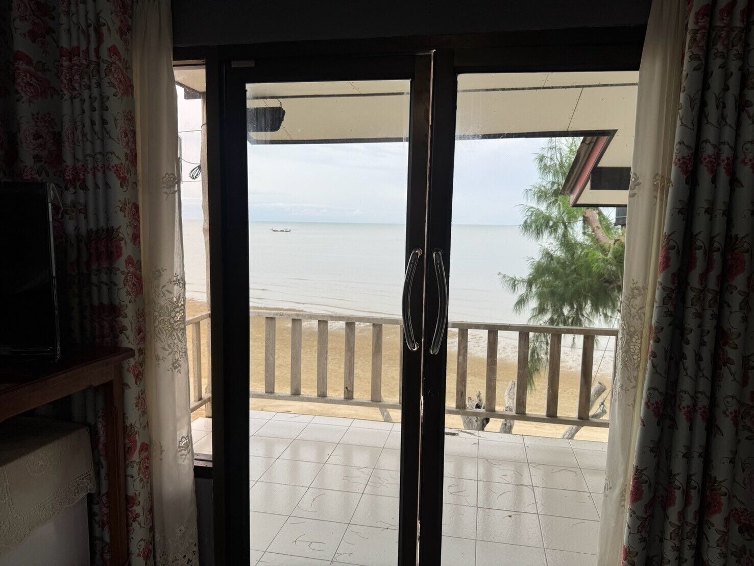 A room with a view of the sea through a sliding glass door.