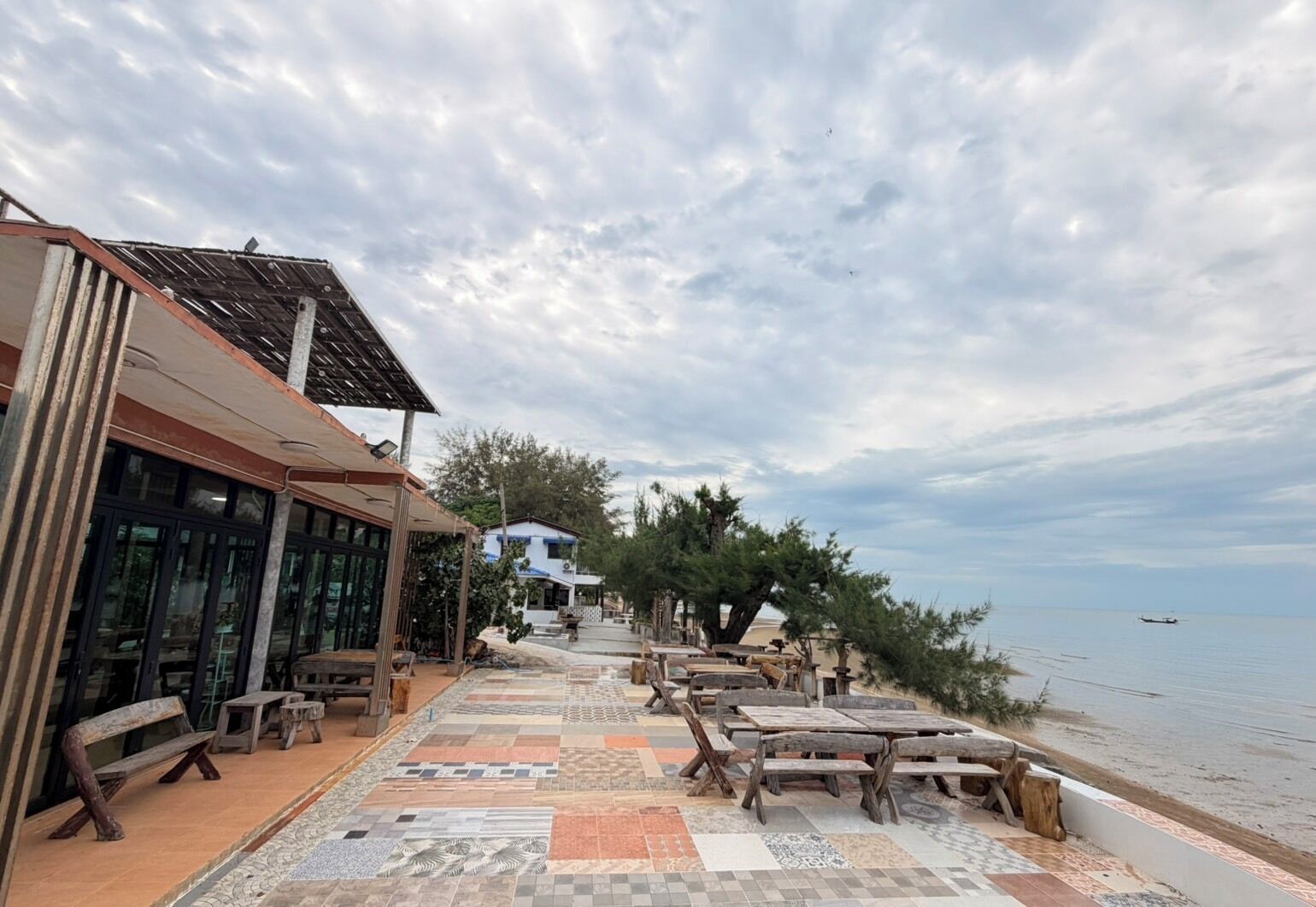 A seaside terrace with outdoor seating and a view of the sea.