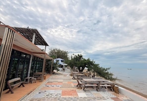 A seaside terrace with outdoor seating and a view of the sea. - Rungarun Resort (Chaiya)