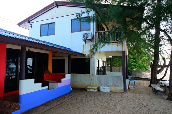 A two-story building with a balcony, outdoor seating, and a staircase leading to the upper level.