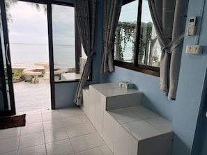 A room with a view of the beach, a small table, a bench, and a thermostat on the wall. - Rungarun Resort (Chaiya)