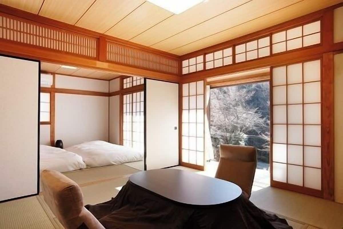 A traditional Japanese room with tatami flooring, a low table, and sliding doors.