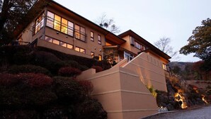 A modern two-story building with a beige exterior, large windows, and a stone base. - Hakone Fura (Hakone)
