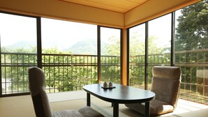 A room with tatami flooring, a low table with two cups, and a cushioned chair. - Hakone Fura (Hakone)