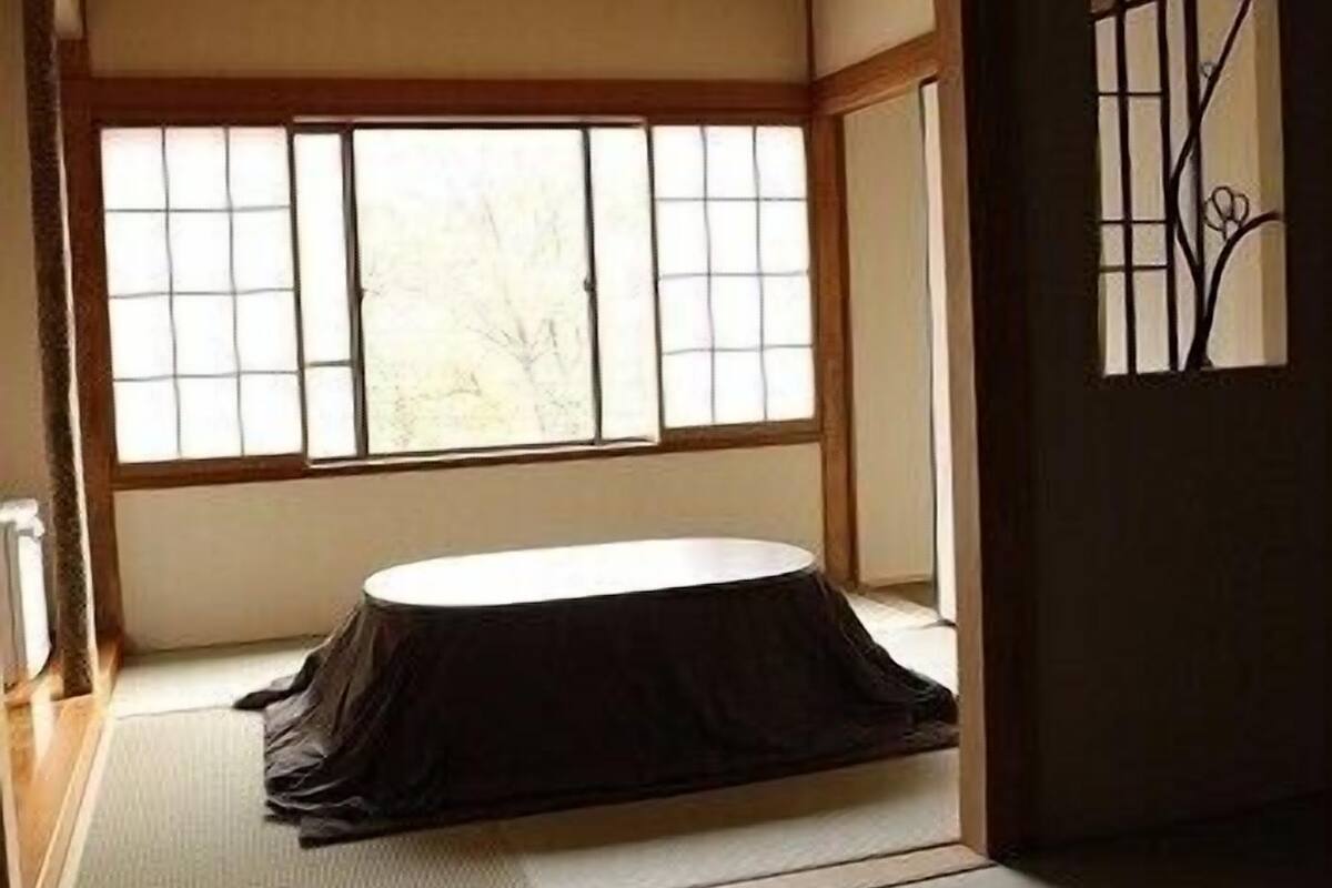 Una habitación tradicional japonesa con suelo de tatami, una mesa baja y una ventana con puertas correderas shoji.