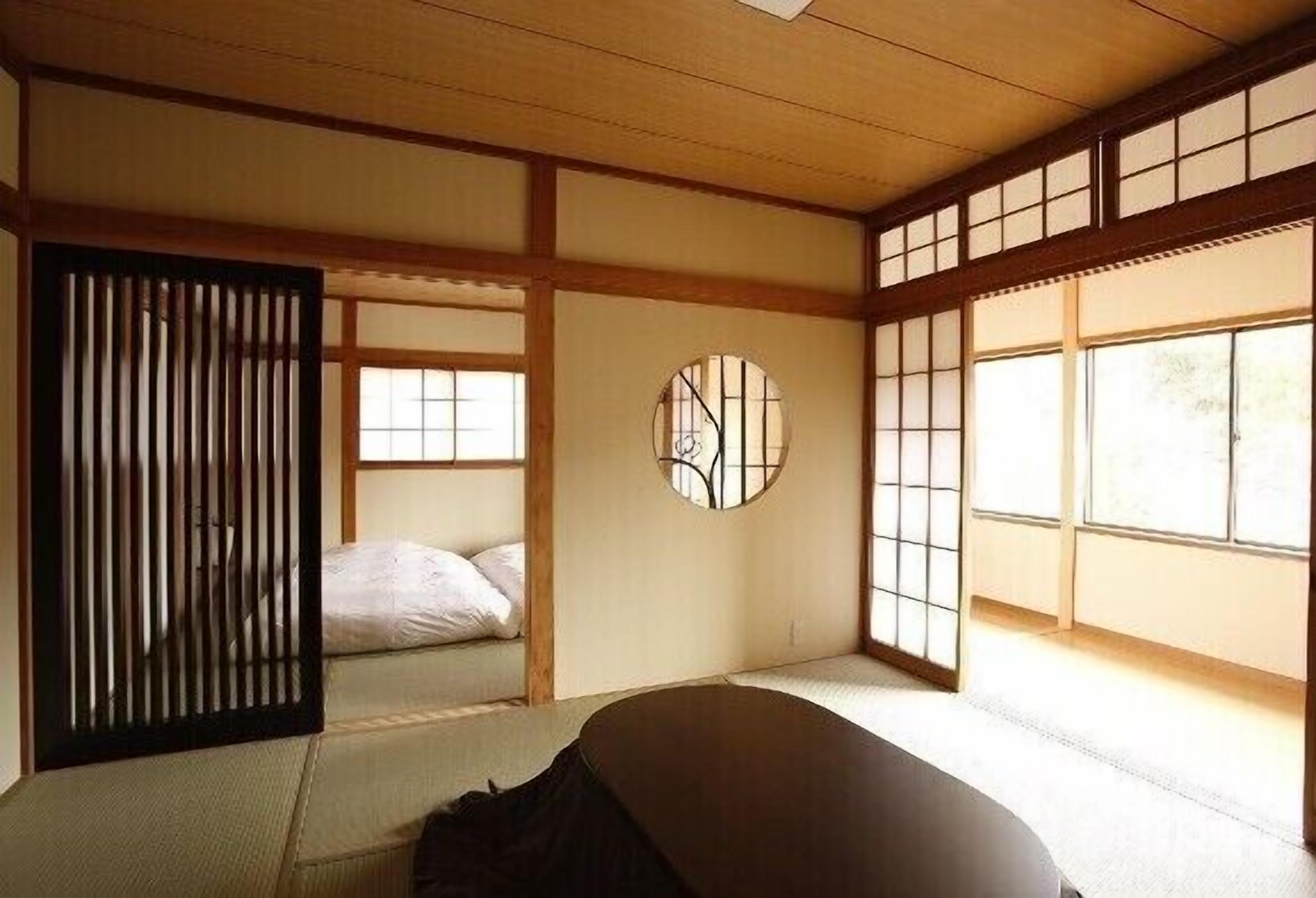 A traditional Japanese room with tatami flooring, sliding doors, and a futon bed.