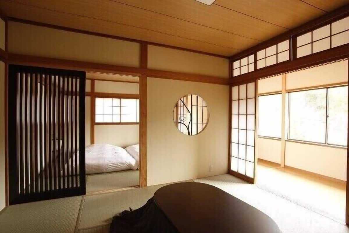 A traditional Japanese room with tatami flooring, sliding doors, and a futon bed.