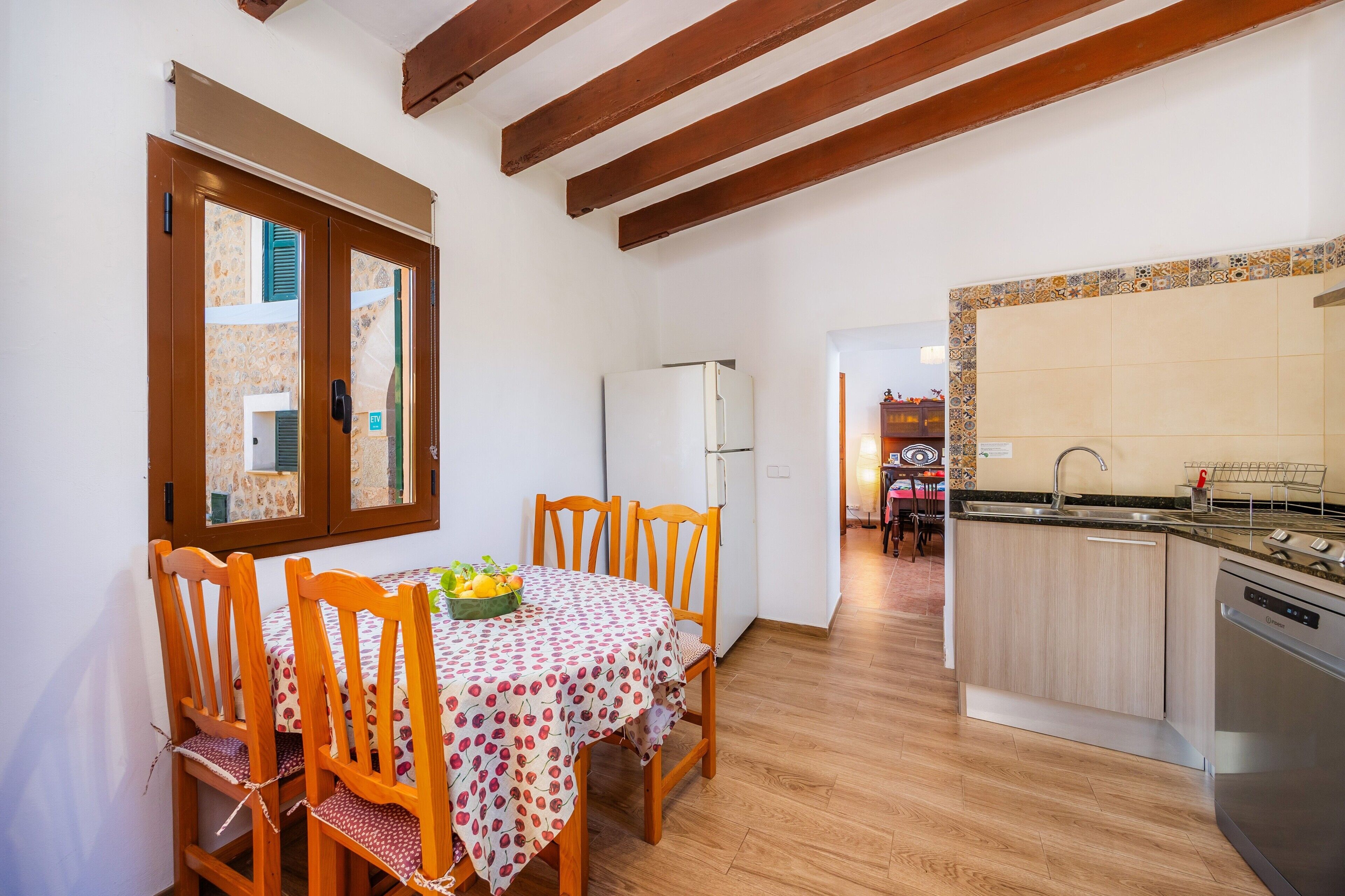 A kitchen with wooden cabinets, a built-in dishwasher, and a dining area with a table and chairs.