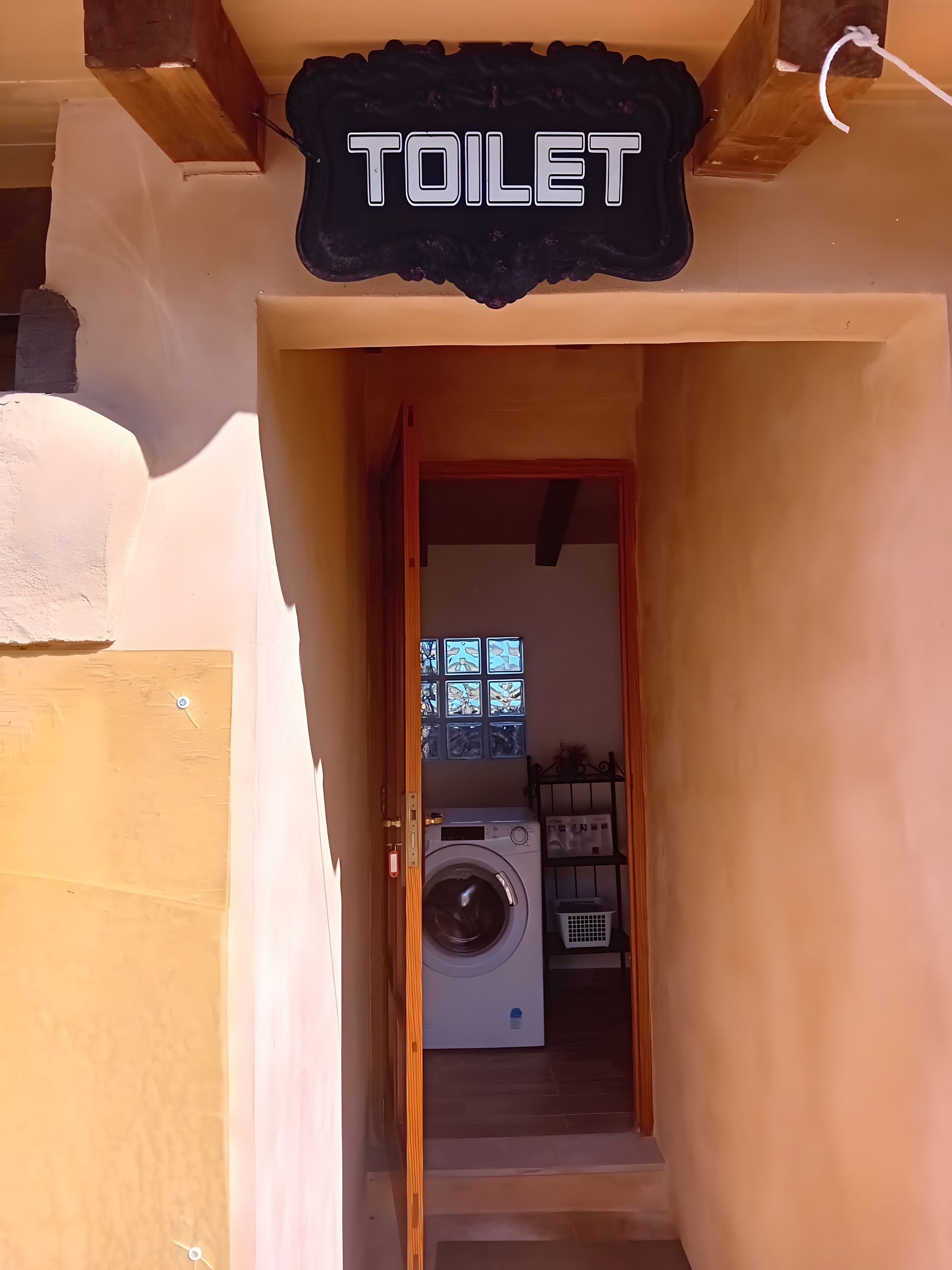 A hallway leading to a laundry area with a washing machine and a shelf with laundry supplies.