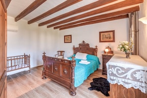 Un dormitorio con cama de madera, una mesita de noche, un aparador y una cuna.