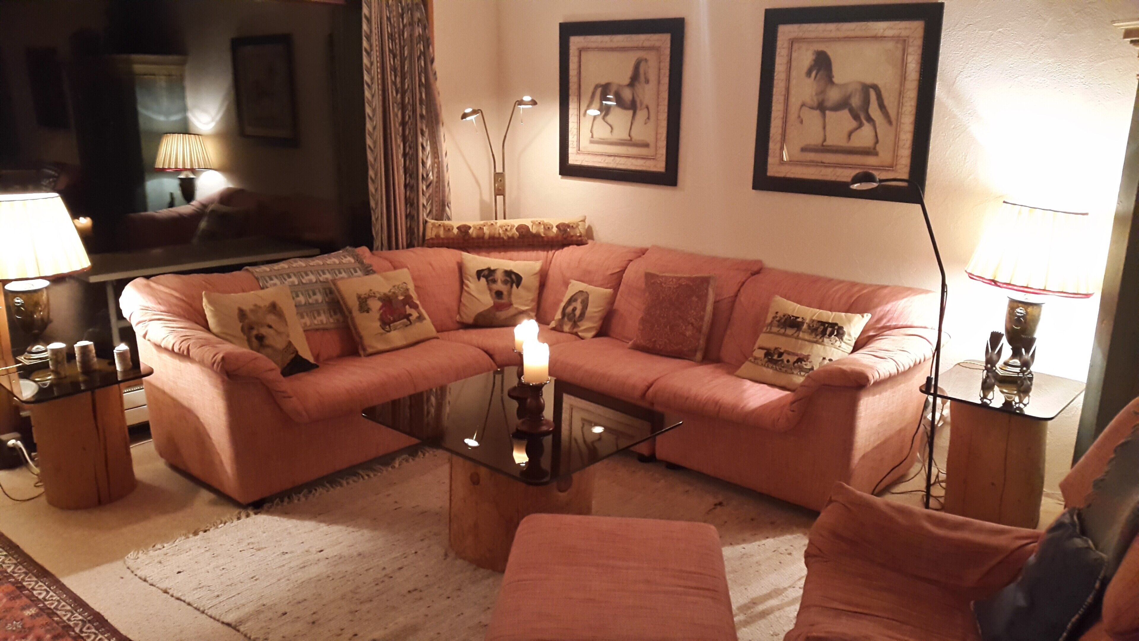 A living room with a pink sofa, a glass coffee table, and a lit candle.