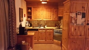 A kitchen with wooden cabinets, a sink, a stove, and a coffee maker. - Vacation flat in idyllic location — Casa Ogna (Klosters)