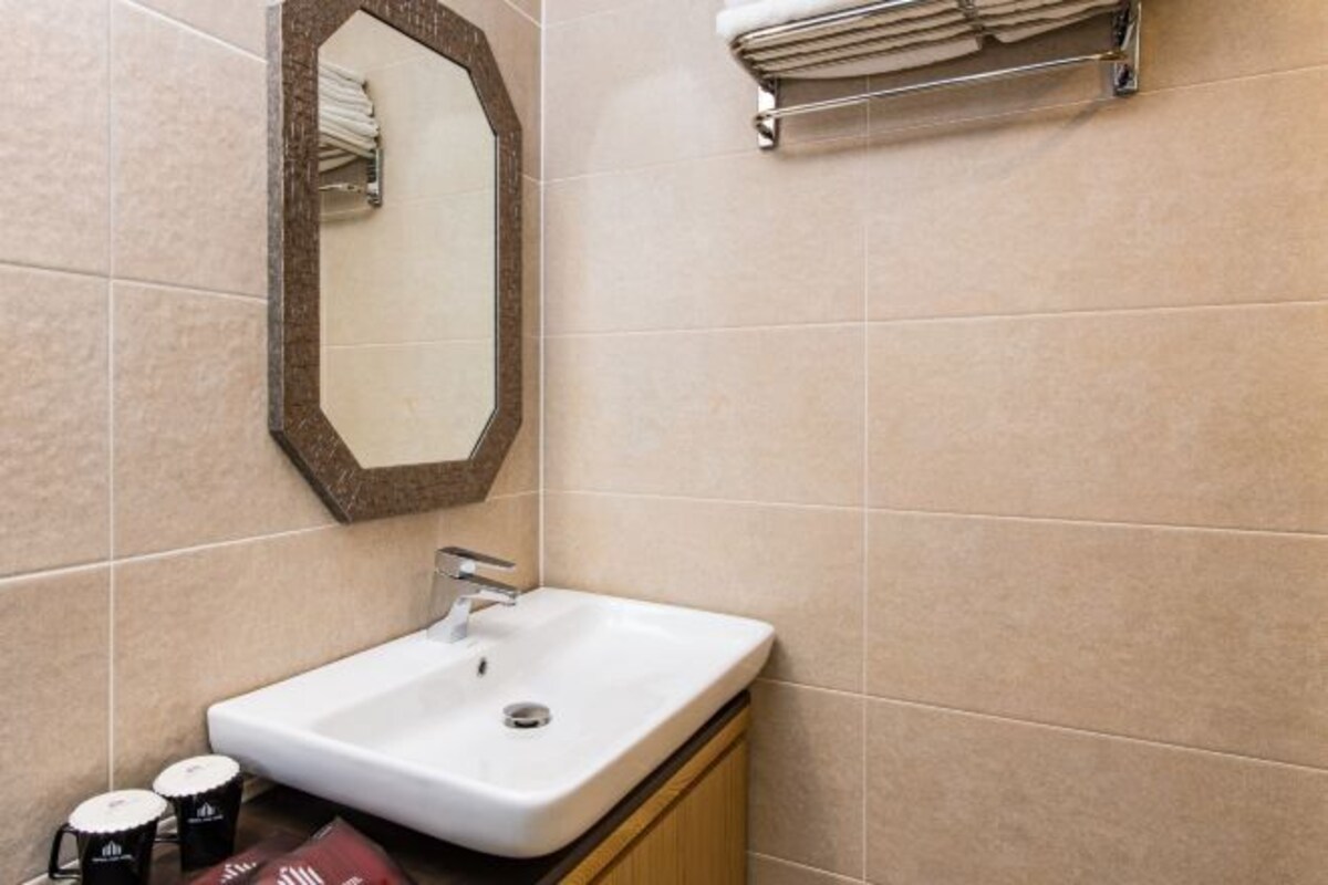 Un baño con lavamanos blanco, espejo y perchero.