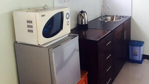 Cocina pequeña equipada con refrigerador, microondas y hervidor.