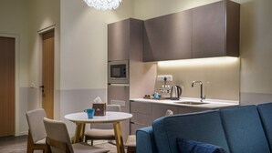 A modern hotel room with a kitchenette, a dining area with a round table and chairs, and a blue sofa. - Bahari Parade Hotel Managed By The Ascott Limited (George Town)