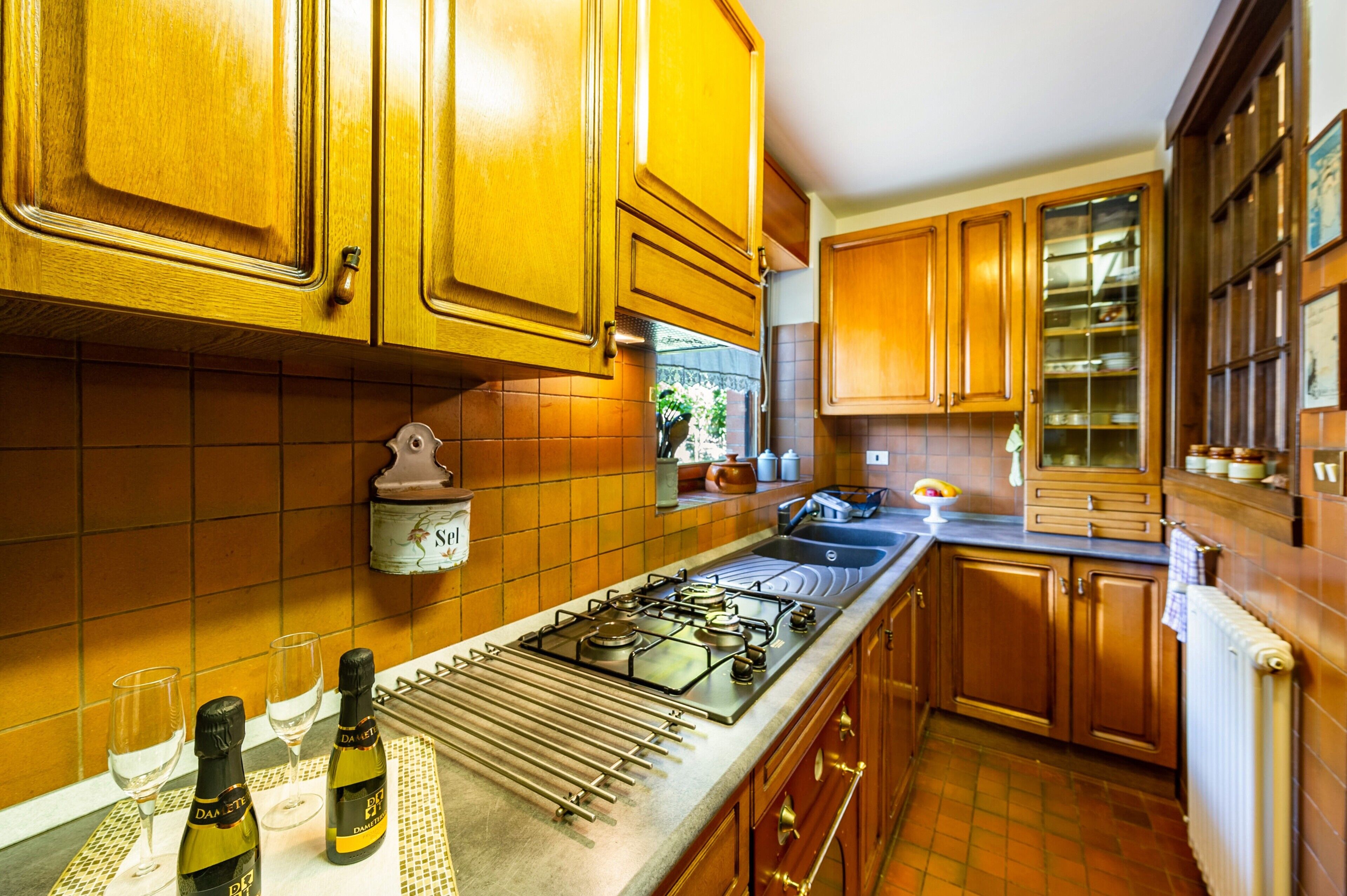 A kitchen with wooden cabinets, a gas stove, and wine bottles.