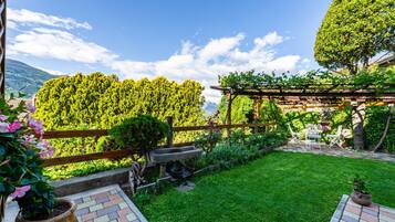 Un jardin agrémenté d’une pergola, d’un banc en pierre et d’une pelouse verdoyante.