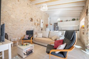 Ein Wohnzimmer mit Steinwand, einer Couch, einem Sessel, einem Couchtisch und einem Fernseher.