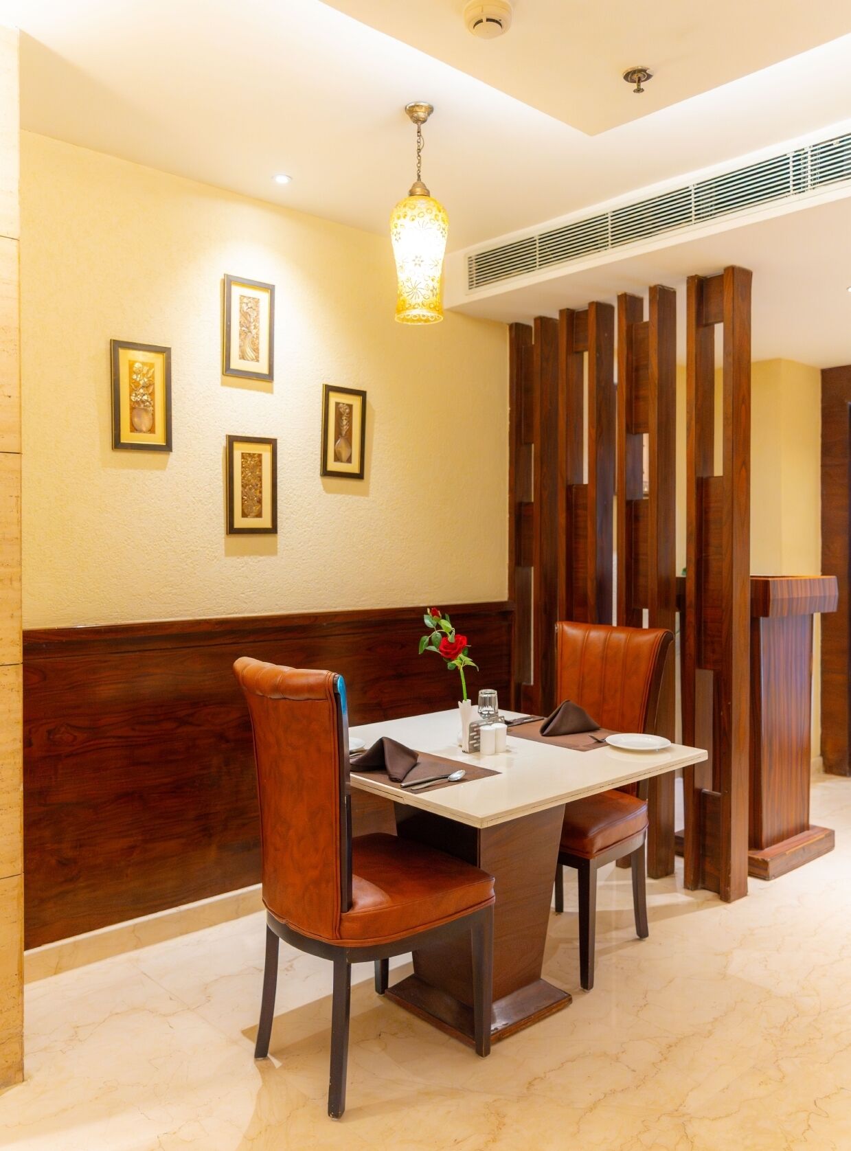 A dining area with a marble floor, wooden paneling, and framed artwork on the wall.
