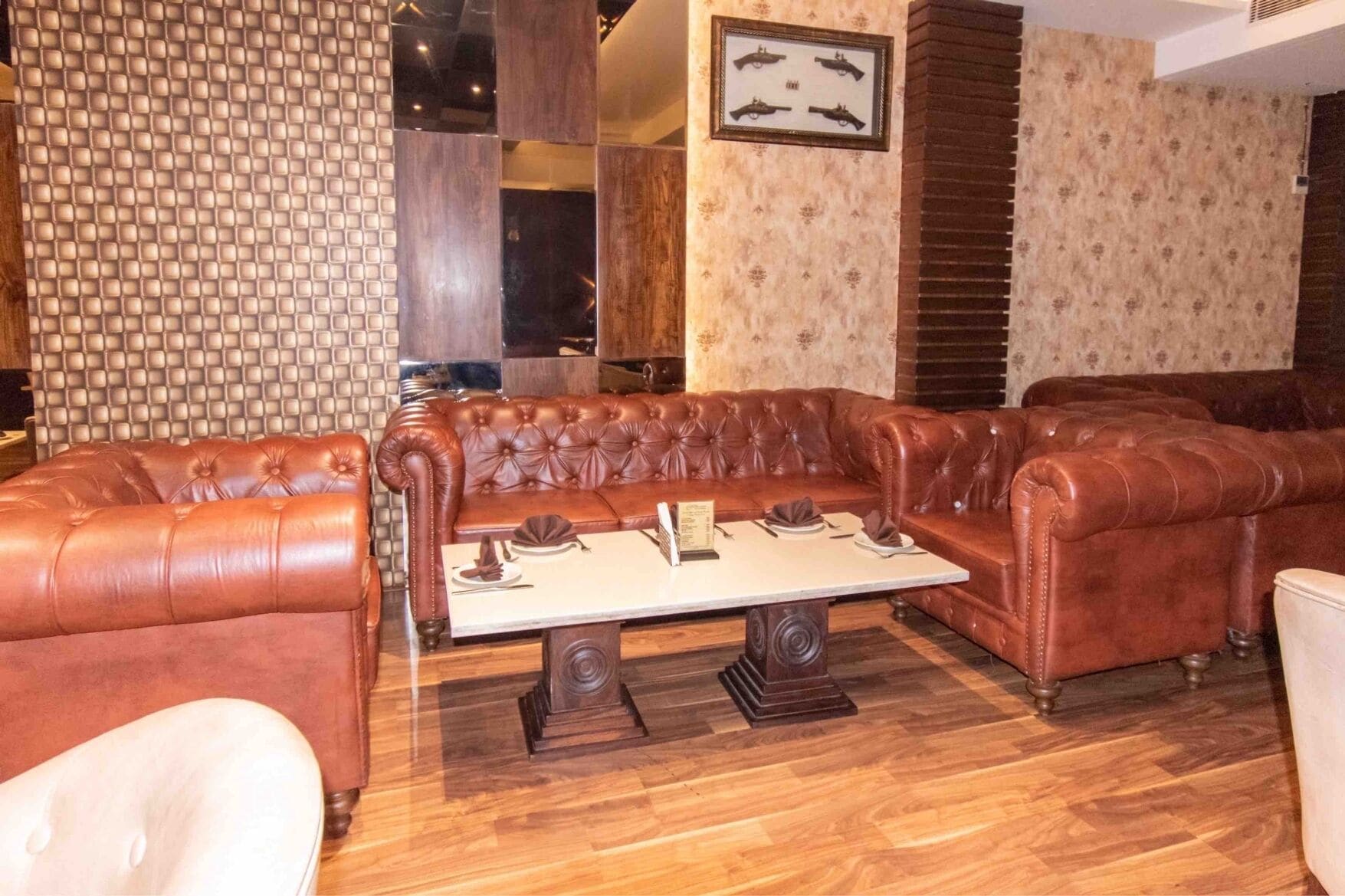 A room with a brown leather sofa set, a wooden coffee table, and patterned wallpaper.