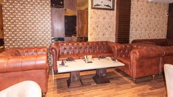 A room with a brown leather sofa set, a wooden coffee table, and patterned wallpaper.