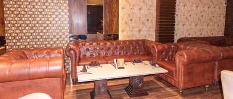 A room with a brown leather sofa set, a wooden coffee table, and patterned wallpaper.