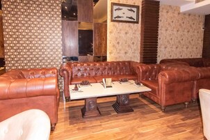Una habitación con un sofá de cuero marrón, una mesa de centro de madera y un papel tapiz estampado.