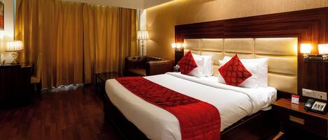 A hotel room with a large bed, bedside tables, a desk, and a chair.