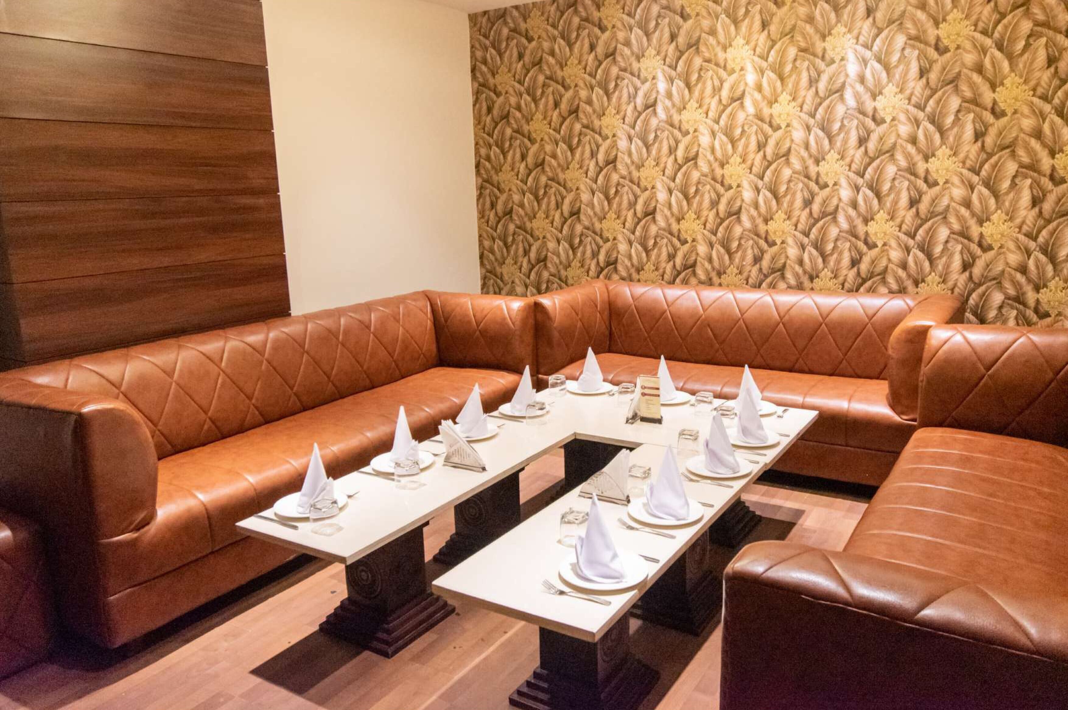 A brown leather sofa set with a table in the center, surrounded by white napkins and silverware.