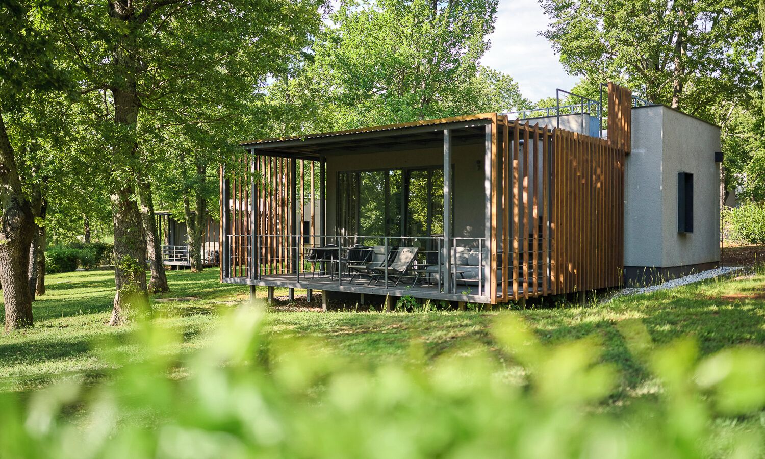 A modern outdoor structure with a covered seating area and a small building.