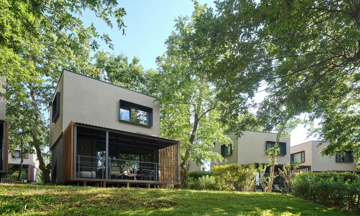 A modern building with a flat roof, large windows, and a covered outdoor area with seating.