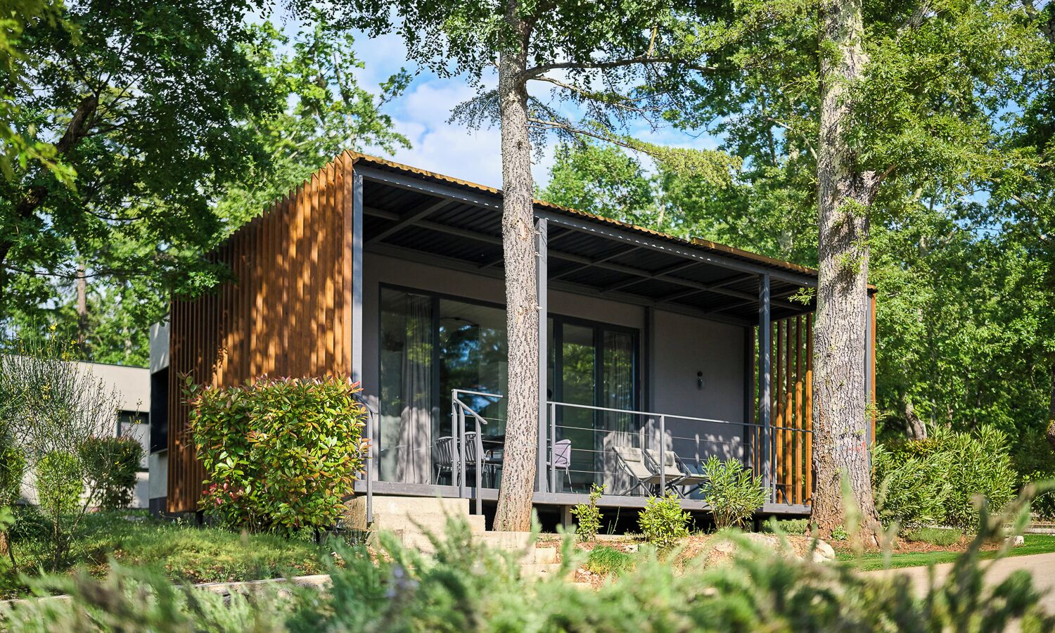 A modern house with a balcony, large windows, and a wooden exterior.