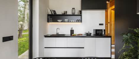 A modern kitchen with white cabinets, black countertops, and a black backsplash. There is a dining area with a wooden table and chairs.