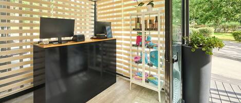 Een modern receptiebalie met een flatscreen televisie, een computer en een glazen vitrine met kleurrijke objecten.