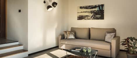A modern living room with a sofa, coffee table, and a painting on the wall.